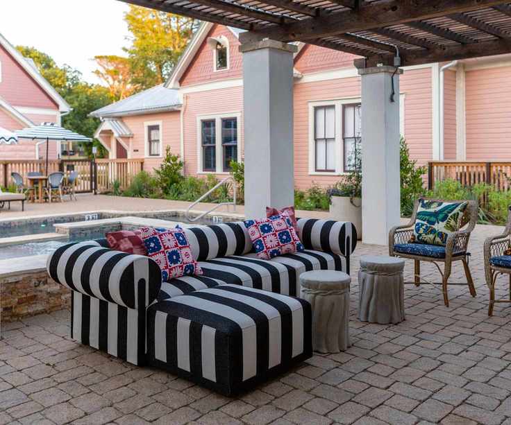 bold striped outdoor couch with a pink pool house and cute parasols
