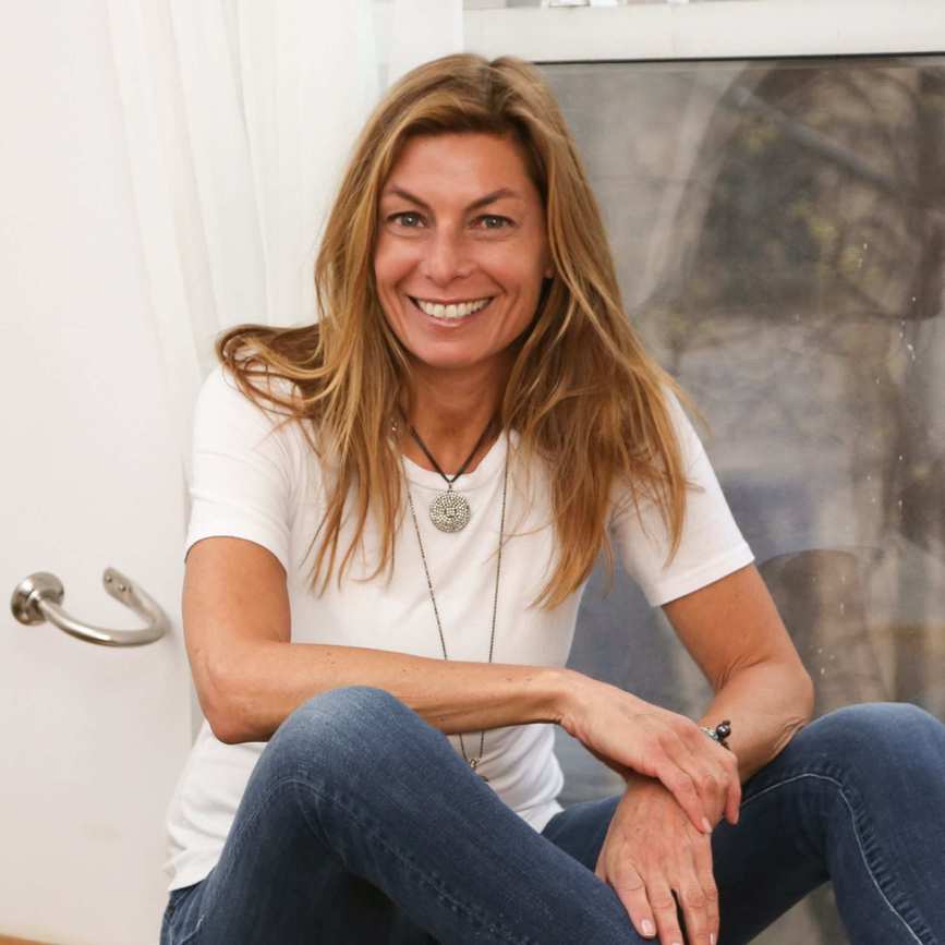 A picture of Hillary Cooper - a woman wearing a white t-shirt and jeans sitting on a windowsill.