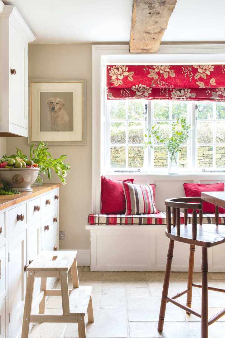 white kitchen with wooden worktops and cabinetry plus window seat with red blinds