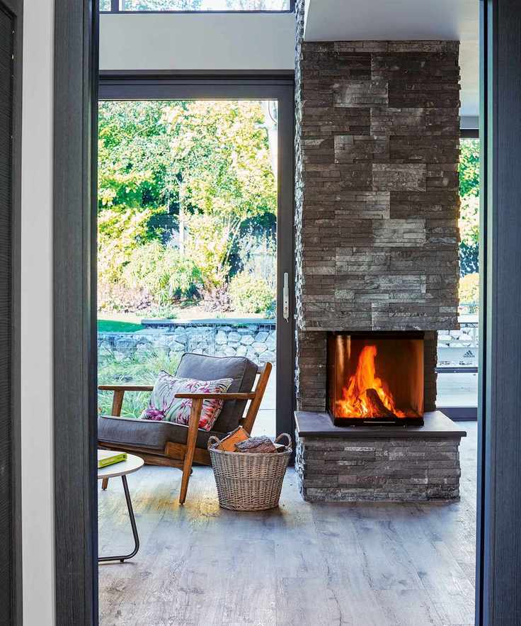 A cozy living room with a lit fire, showcasing beautiful patio doors leading to a garden.