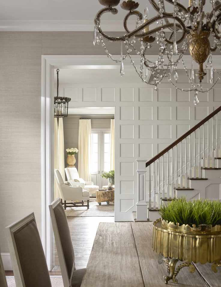 Elegant hallway with chandelier and paneled staircase walls