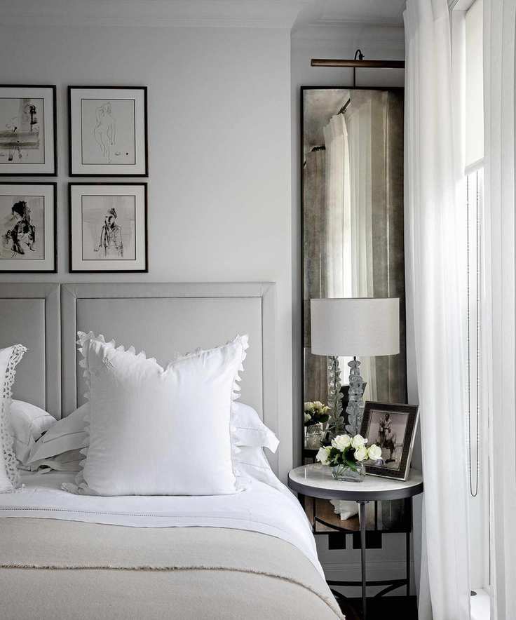 A pale grey bedroom with a headboard and linens