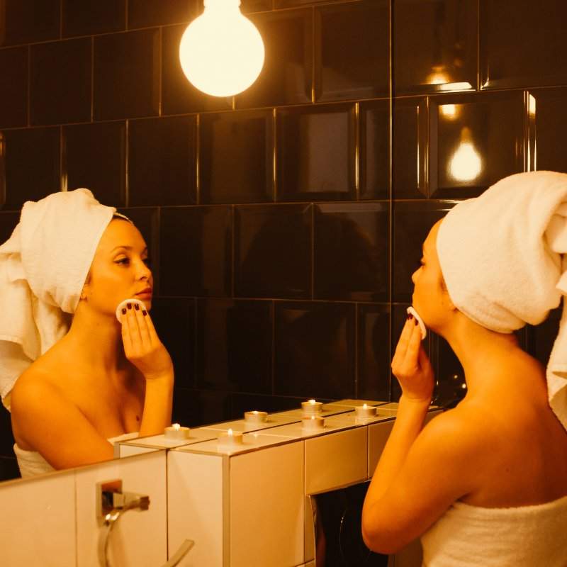 Woman doing her bedtime facial routine in mirror