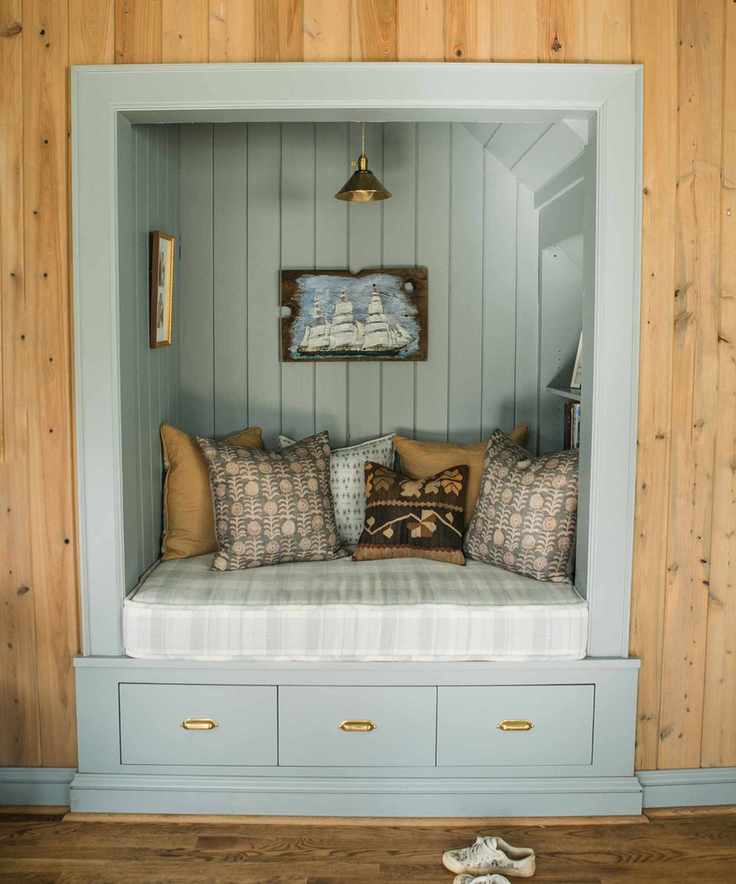 blue paneled reading nook with throw pillows and vintage art