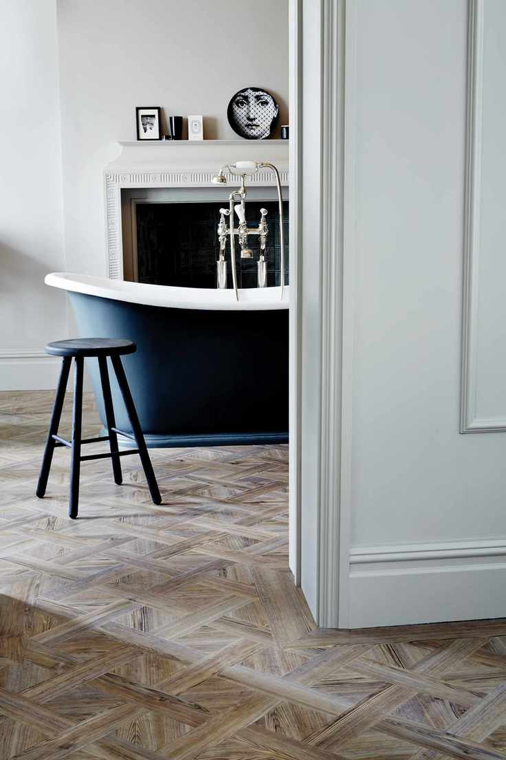 bathroom with Versailles style vinyl wood effect floor, black painted roll top bath, stool, artwork