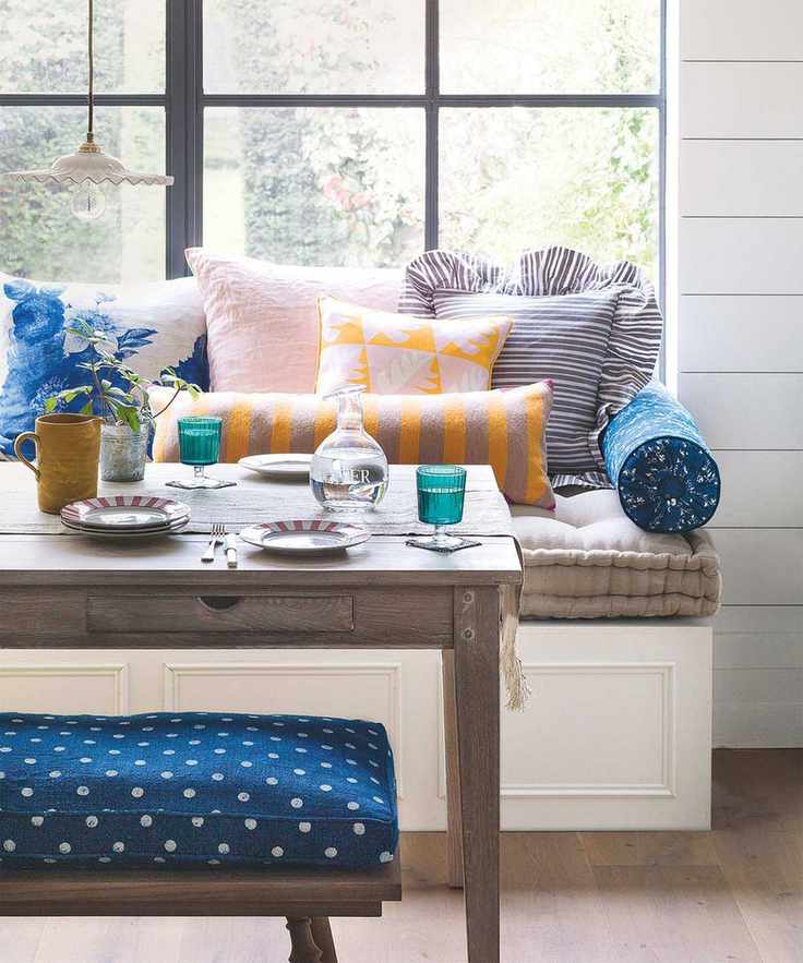 Small dining room with window seat and colored glassware