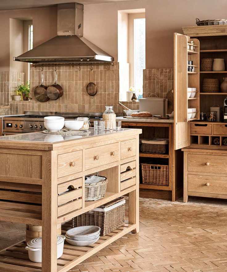 A large solid wood standalone kitchen island in the center of a matching rustic kitchen