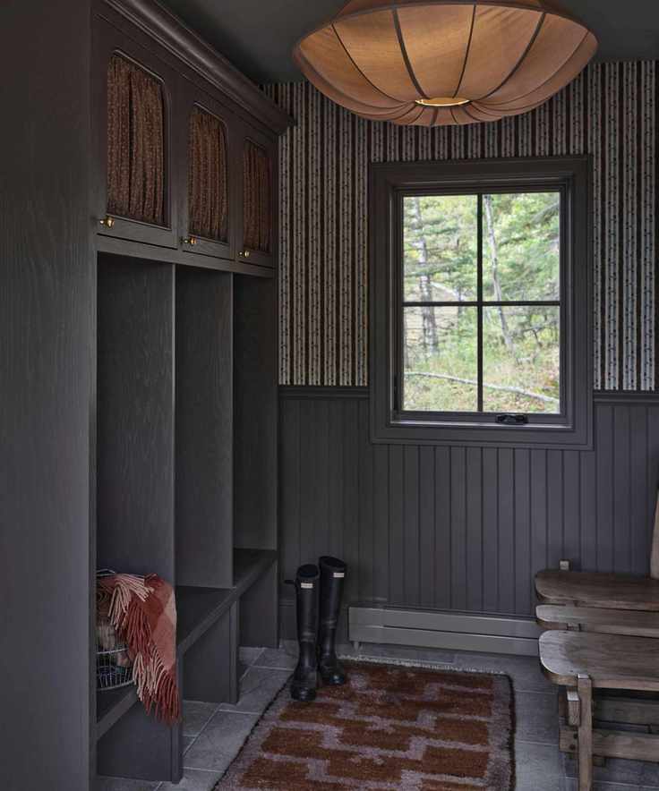 a warm mauve entryway with floral striped wallpaper, half height paneling, limestone floors, a vintage stool an drug and silk pendant light