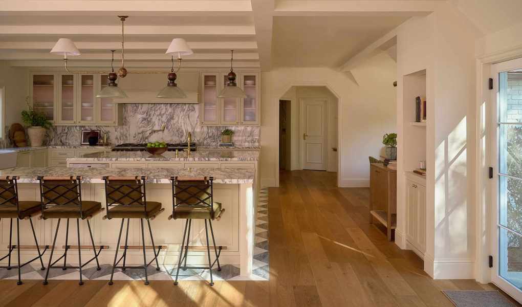 a large open plan neutral kitchen with both wooden and checkerboard flooring to zone the areas