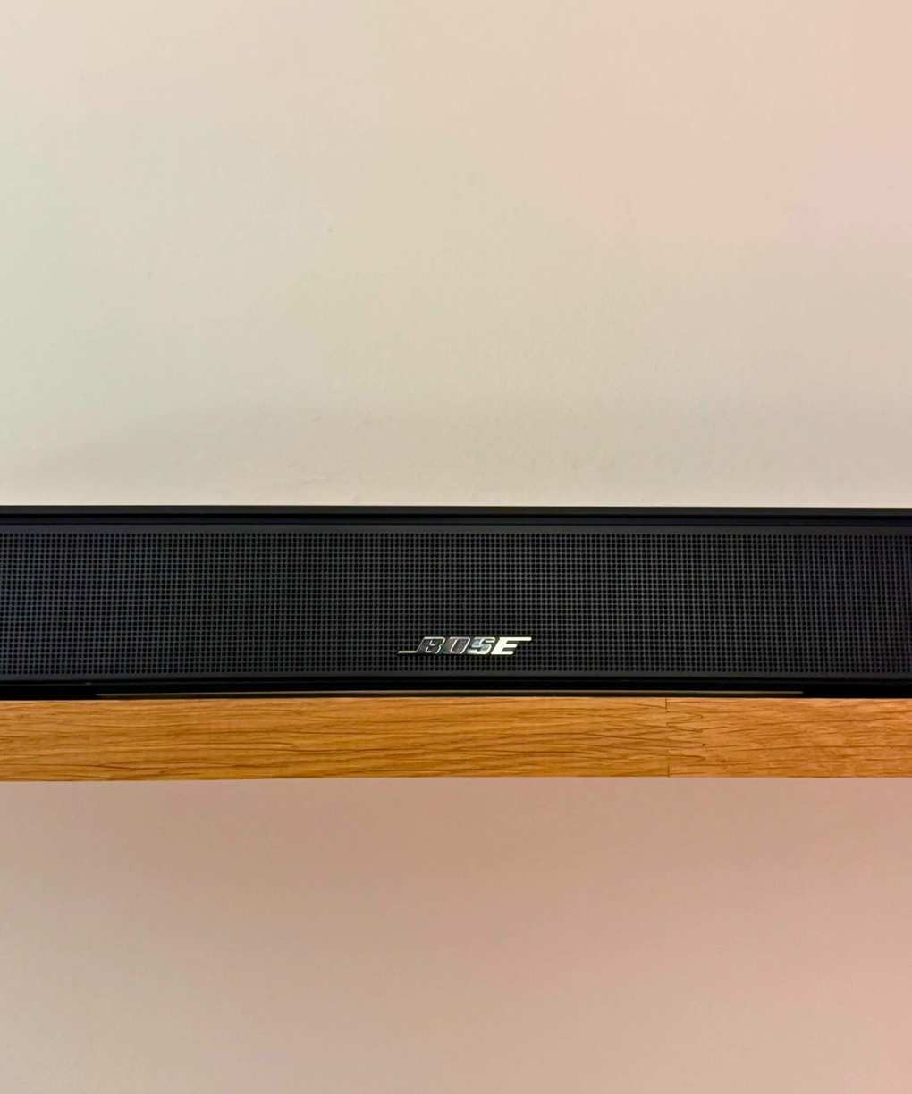 Closeup of the Bose Smart Soundbar on a shelf in front of a white wall.