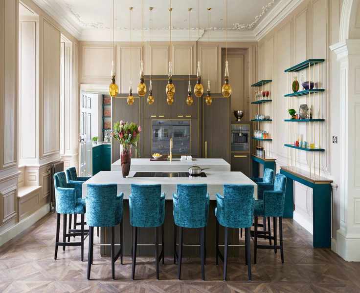 Beautiful wooden parquet in a spacious cream kitchen with blue velvet chairs.