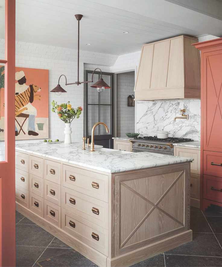 A stylish kitchen featuring a large wooden island, marble countertops, and terracotta accents.