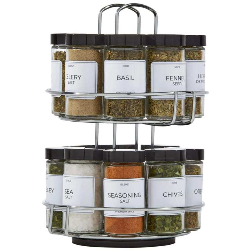 A silver metal revolving spice jar holder filled with spices with black lids and white labels
