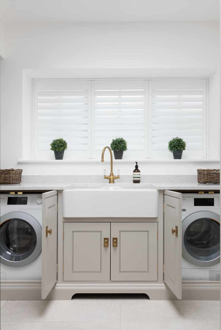 A smart utility room with grey cupboards and brass finishes.