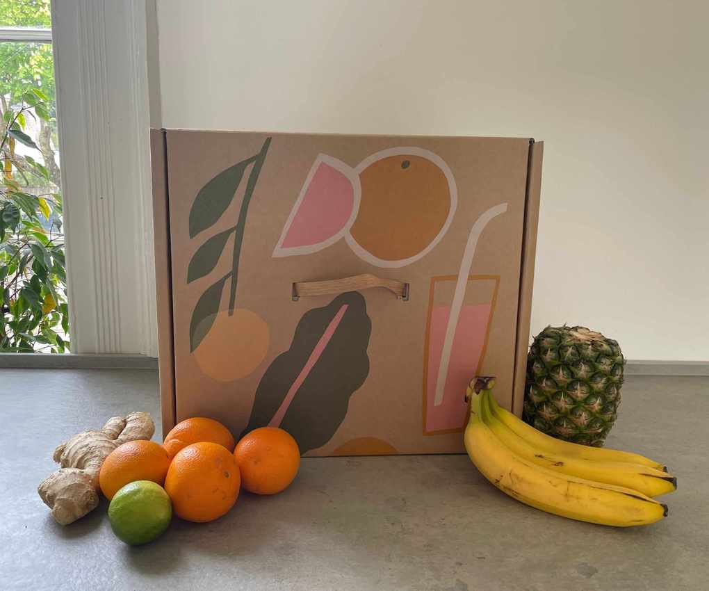 Nama J3 Juicer box on the countertop with fruit around it