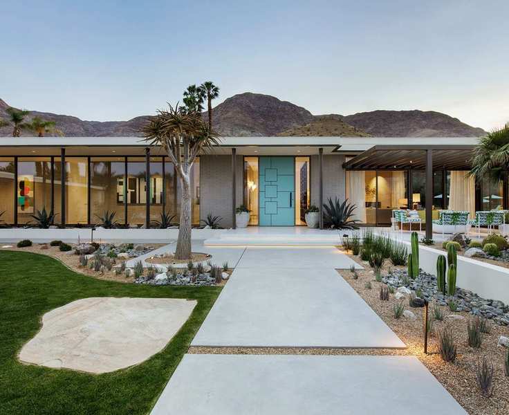 A stylish front porch area with a smooth path leading up to a green door on a modern home