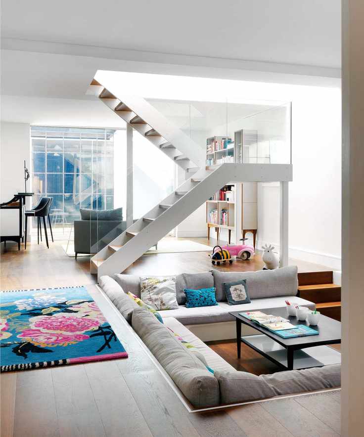 Stylish basement living area with gray furniture and a bright rug