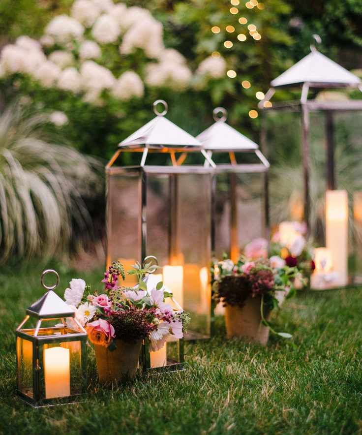 steel candle lanterns on grass with flowers