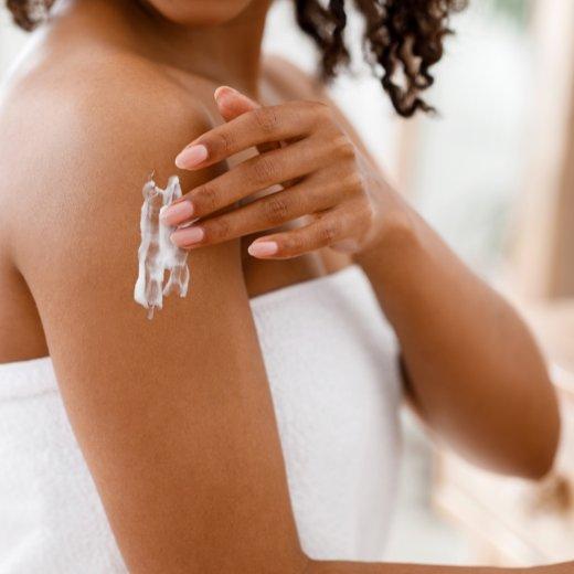 Image of model applying body lotion to their skin