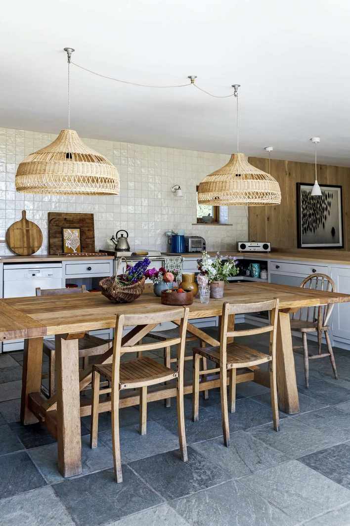 large wooden dining table with lights over in country kitchen diner