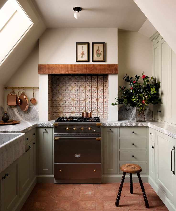 Small sage green kitchen with patterned tiles and terracotta floor with marble worktops