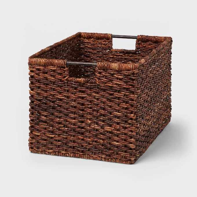 A large dark woven storage basket with cut out handles
