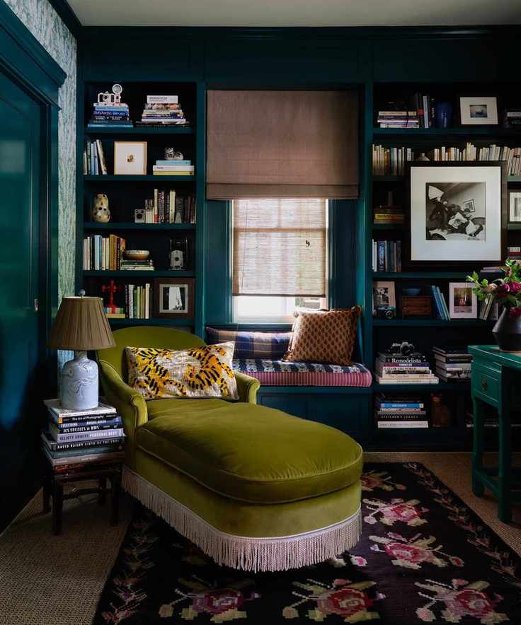 A beautifully styled reading space featuring rich blue bookshelves and cozy furniture.