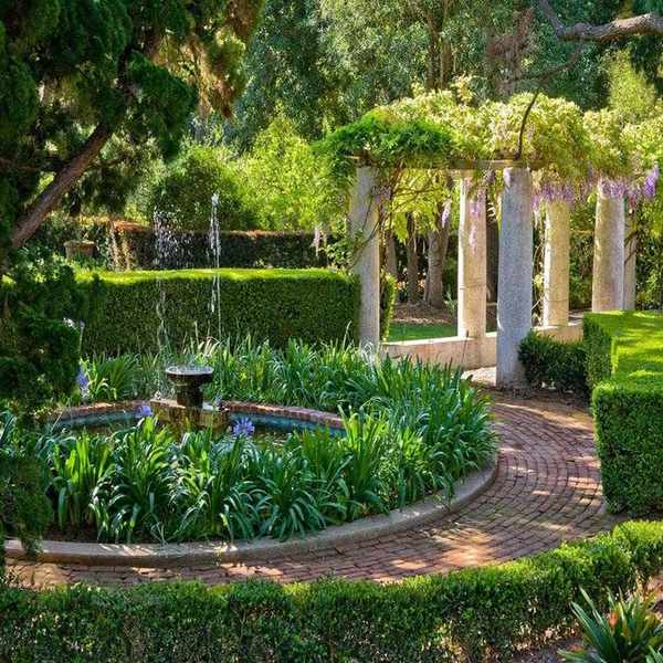 Front walkway ideas featuring wisteria and a paved path curving around a pond.