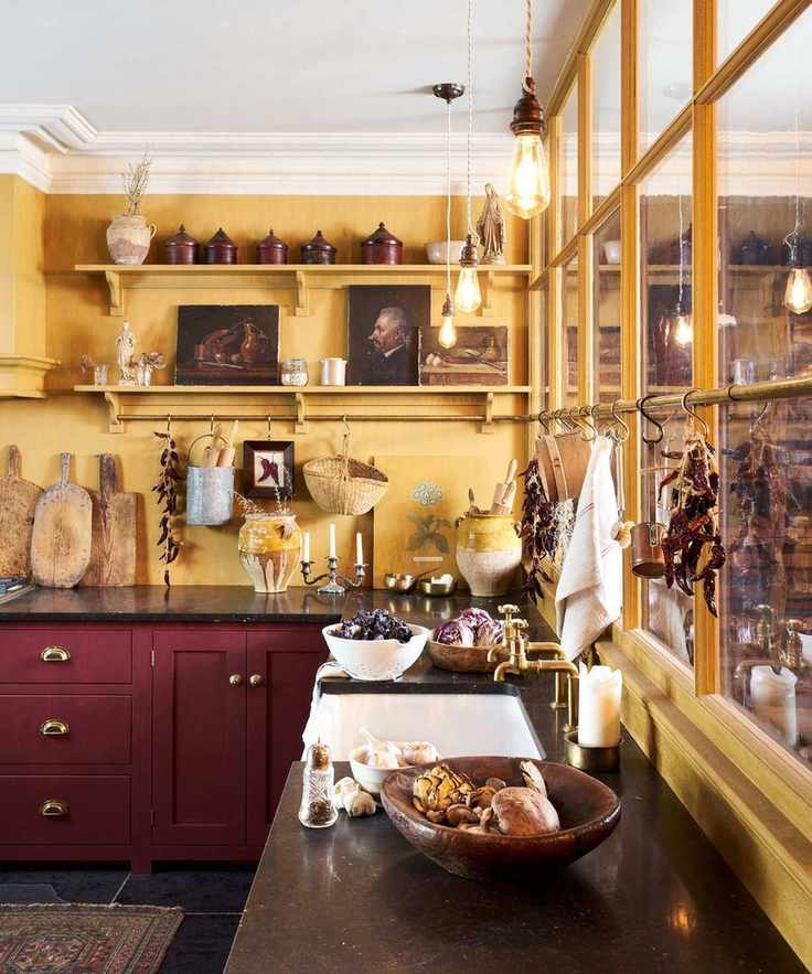 A kitchen with warm yellow walls and dark red cupboards.
