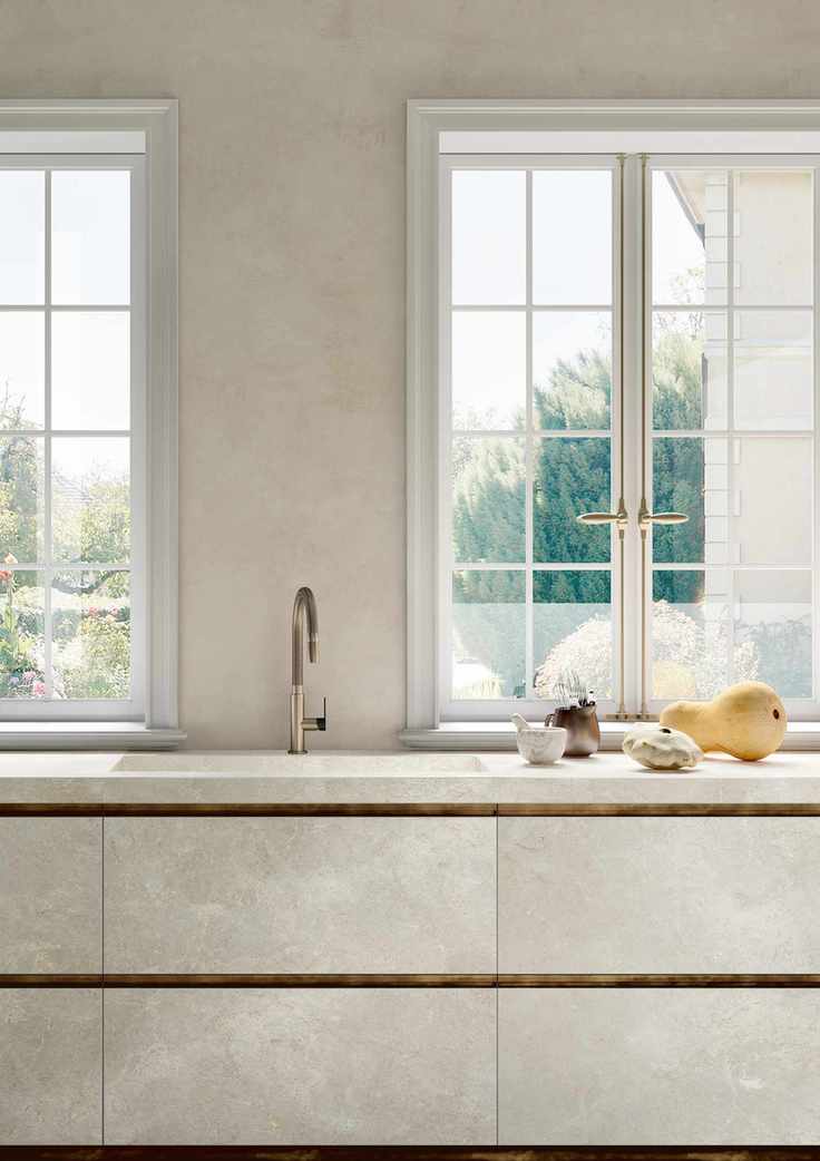Modern, cream kitchen ideas featuring sleek drawers with golden and brass fixtures and large windows.