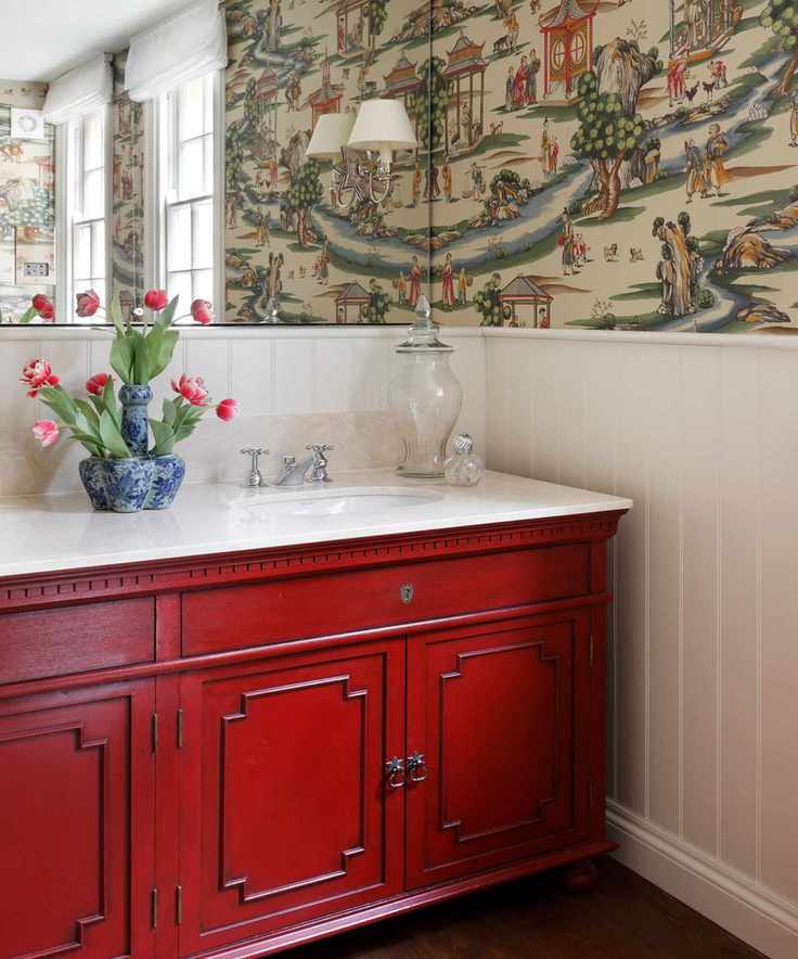 A powder room featuring a red vanity and patterned wallpaper