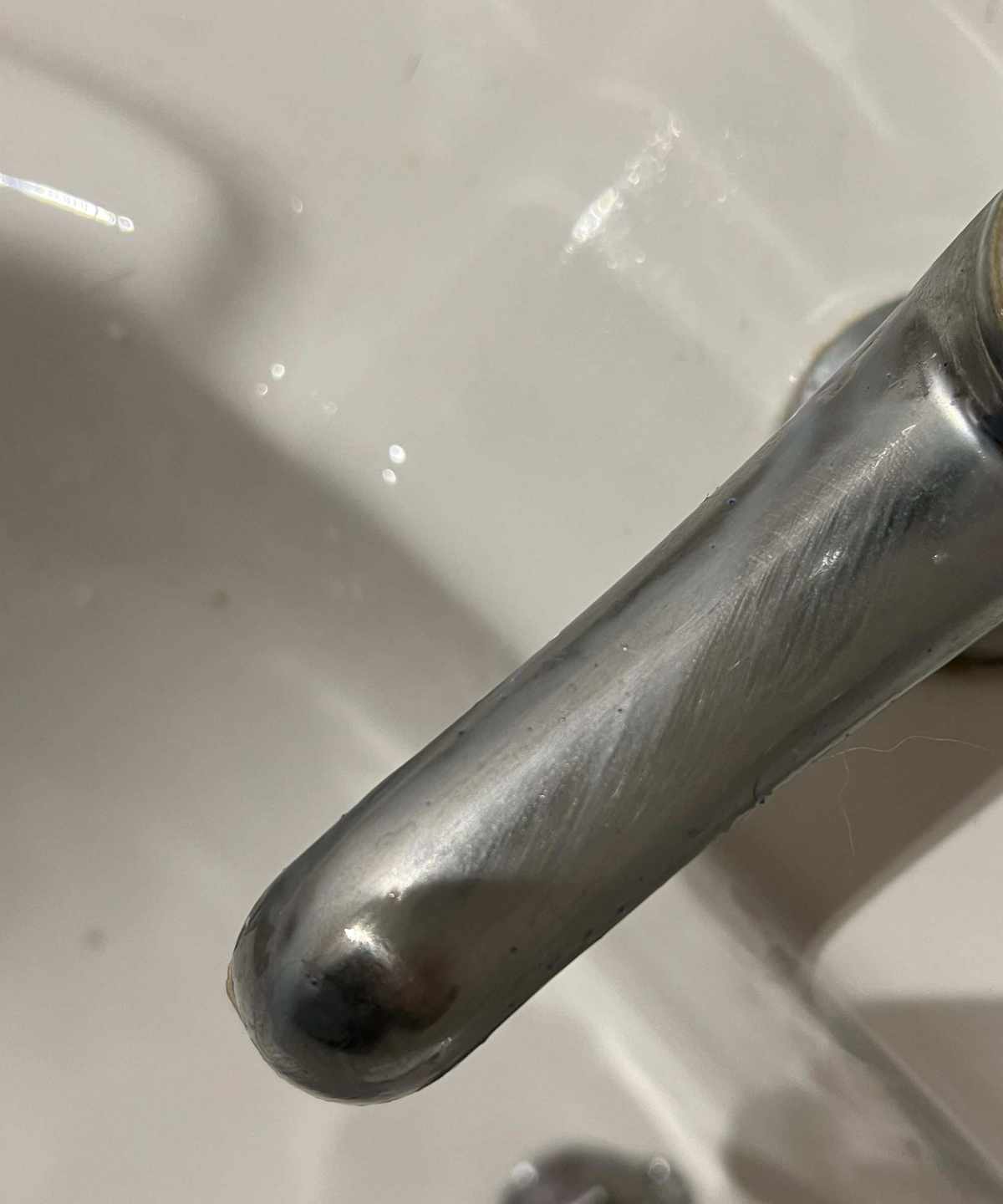 A chrome faucet over a white porcelain sink