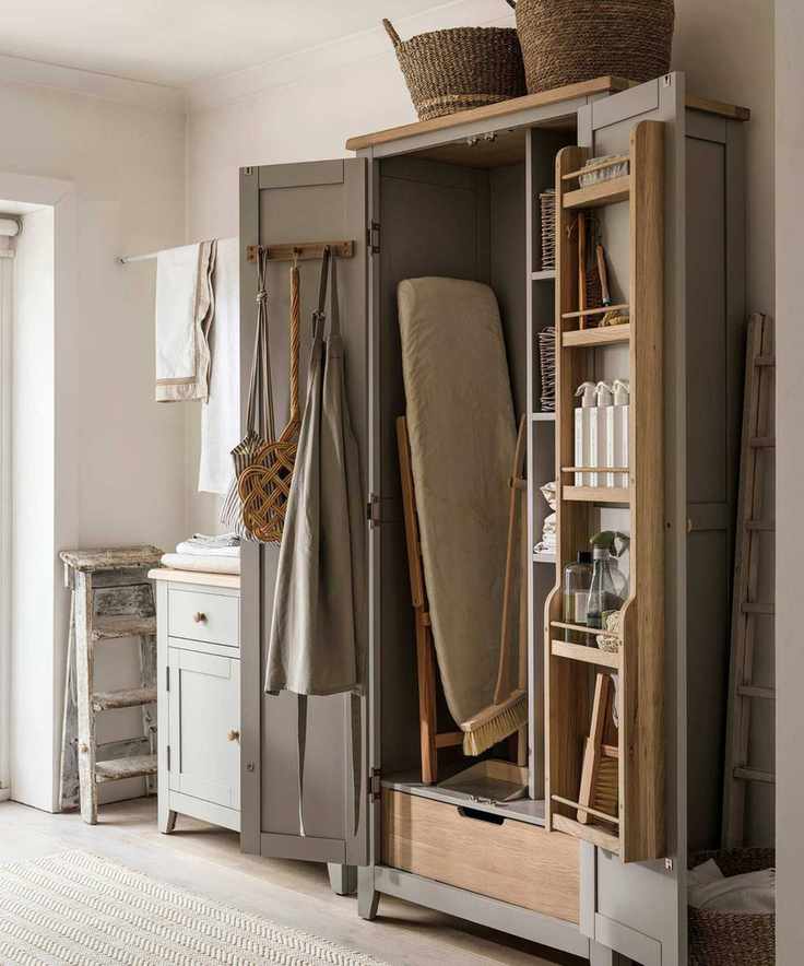 An open wooden storage cabinet filled with non-toxic cleaning supplies and an ironing board.
