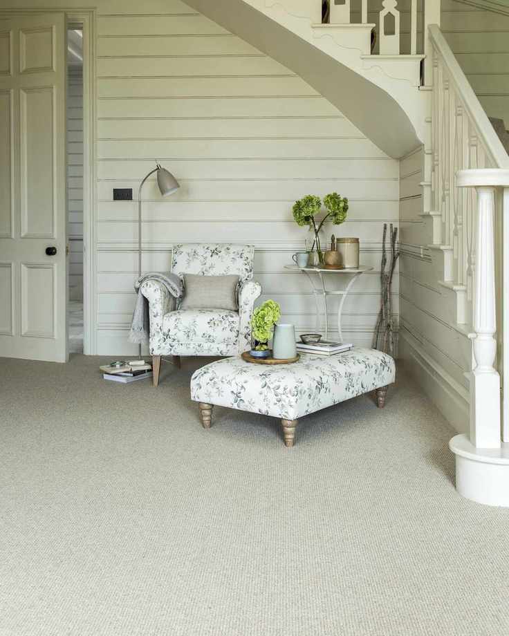 Charming hallway with an armchair and footstool under the stairs