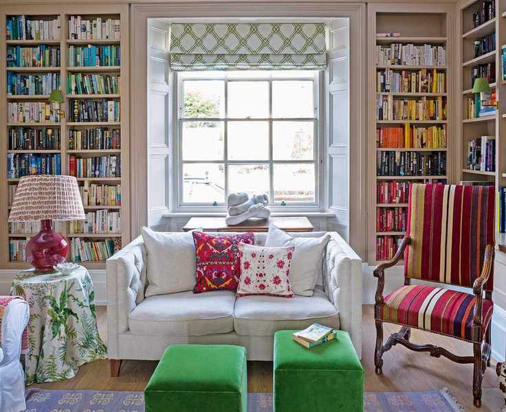 Living room with book lined shelves, sofa, ottomans and striped upholstered chair