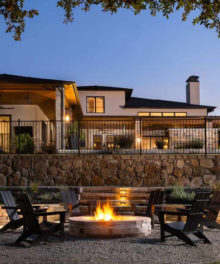 Outdoor seating area in the dark with Adirondack chairs around a firepit