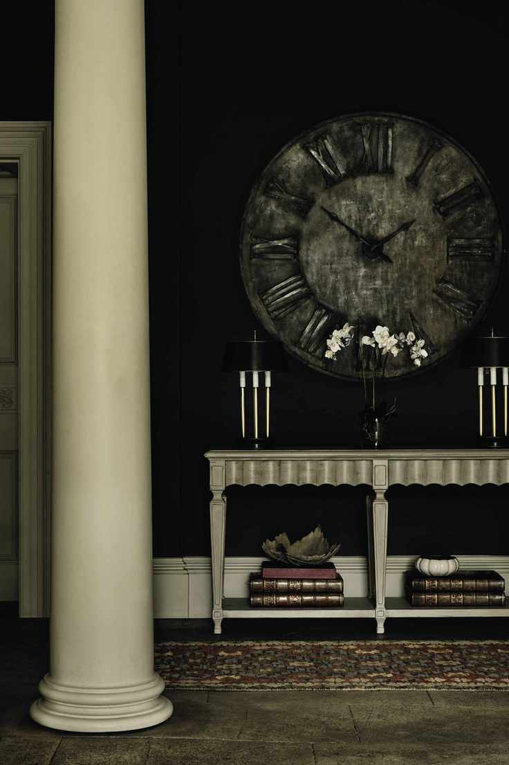black entryway with stone floor, stone pillar, console and large clock