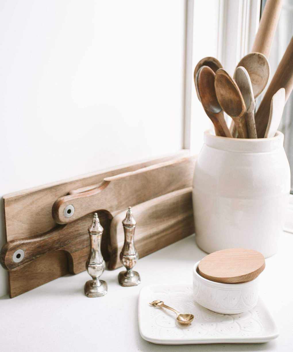 Kitchen chopping boards against a wall with a pot of wooden kitchen utensils