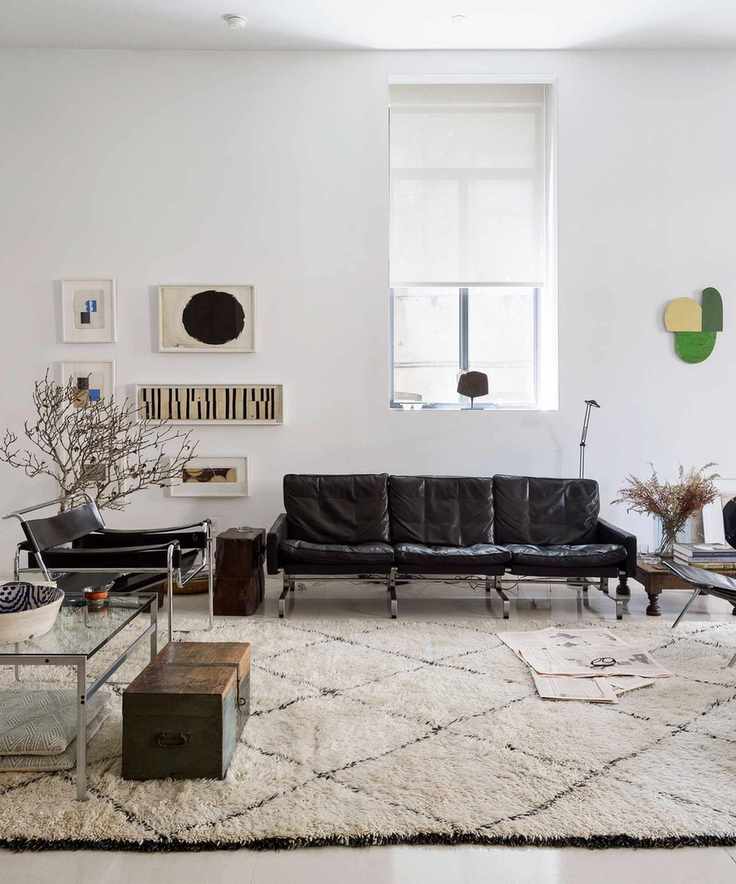 Minimalist beige living room with a sleek black sofa and wall art.