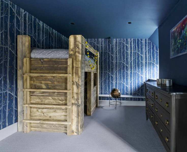 A kids' bedroom with a loft bed and forest-themed wallpaper