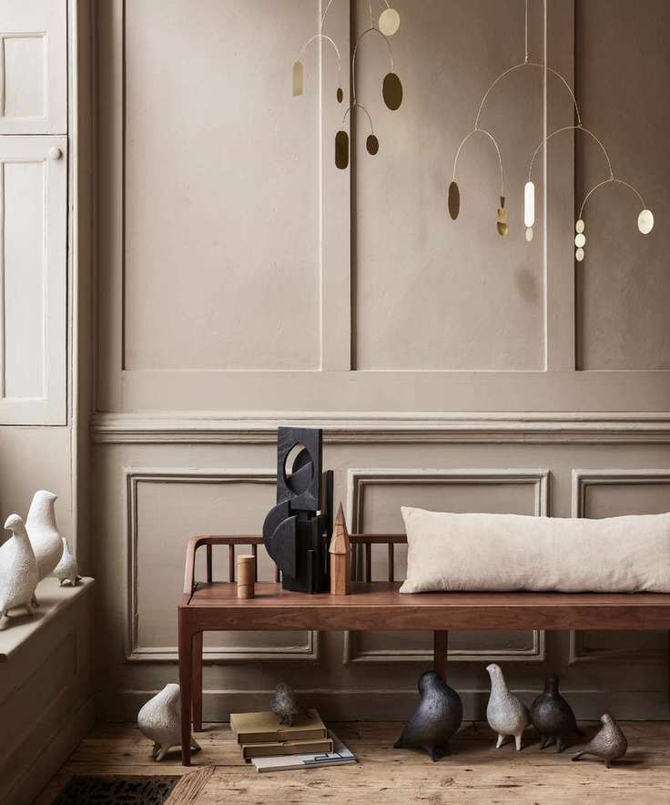 Wooden bench with beige cushion before brown paneling