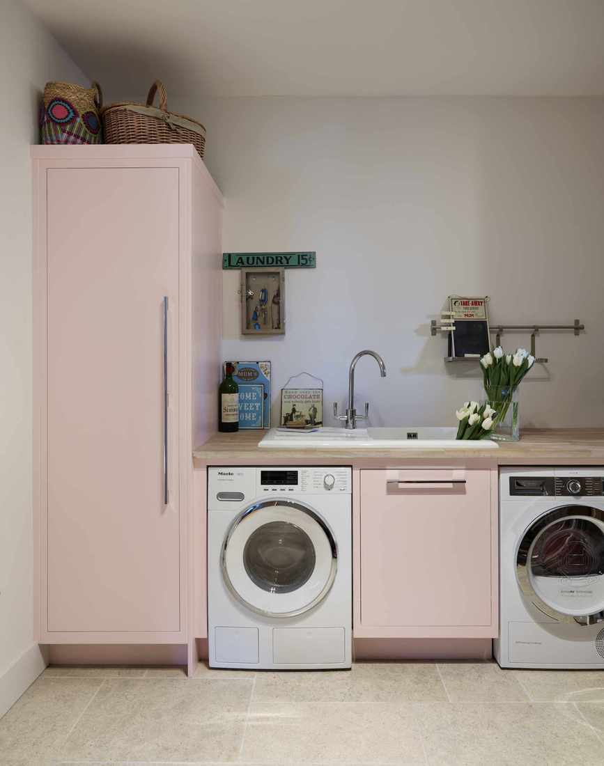 pastel pink laundry room with painted units washing machine and dryer