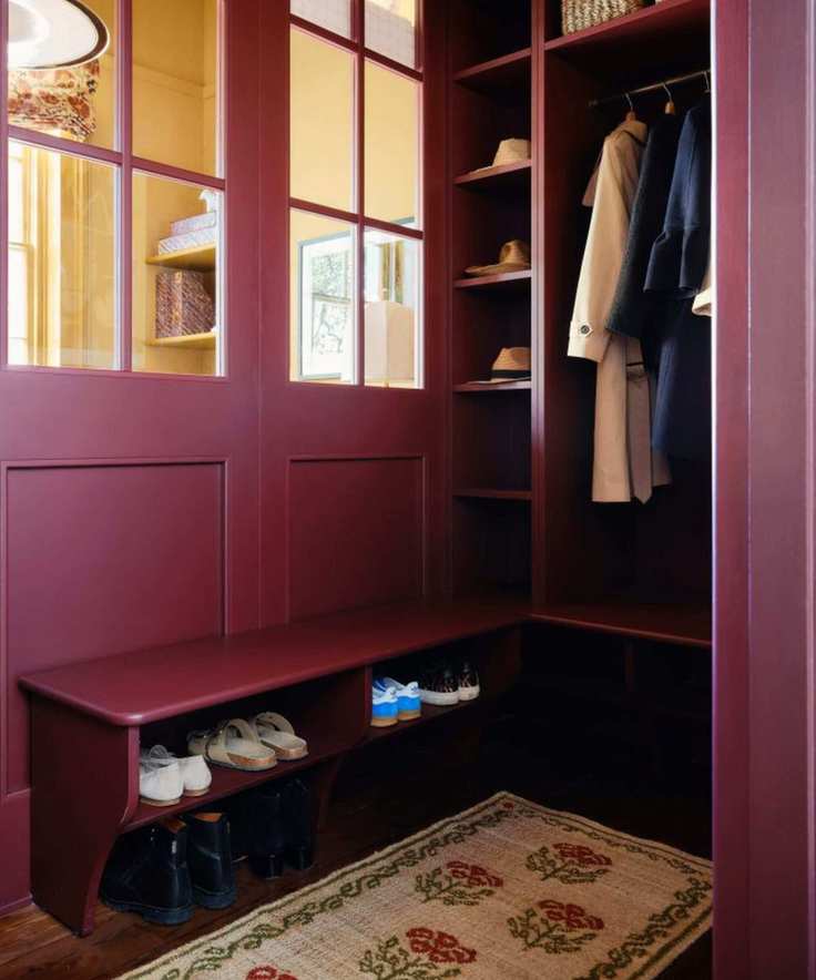 a small boot room in an entryway painted in deep red burgundy paint