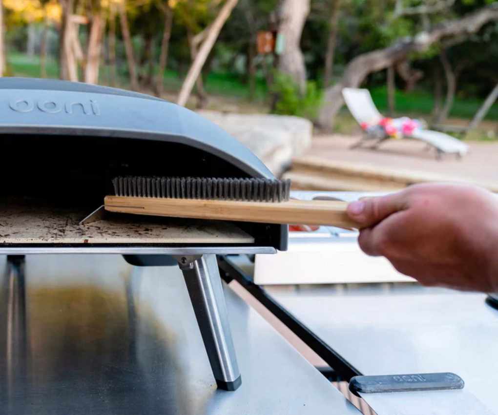 An Ooni brush cleaning an Ooni pizza brush