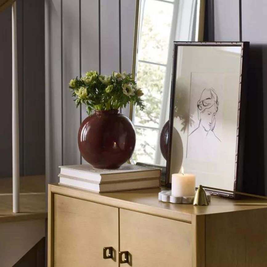 A console table with books, a framed drawing, a vase and a candle