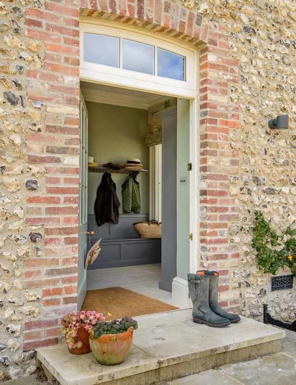 Location is important when designing a mudroom like this one featuring a large door mat and a bench with built in storage
