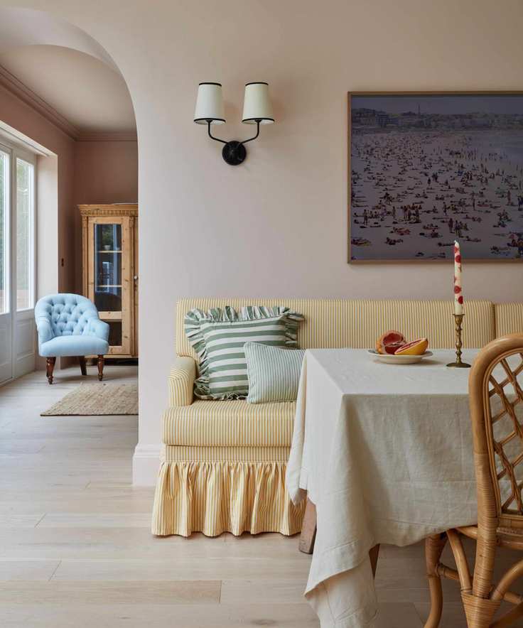 pastel room with a yellow skirted banquette set and pale pink walls