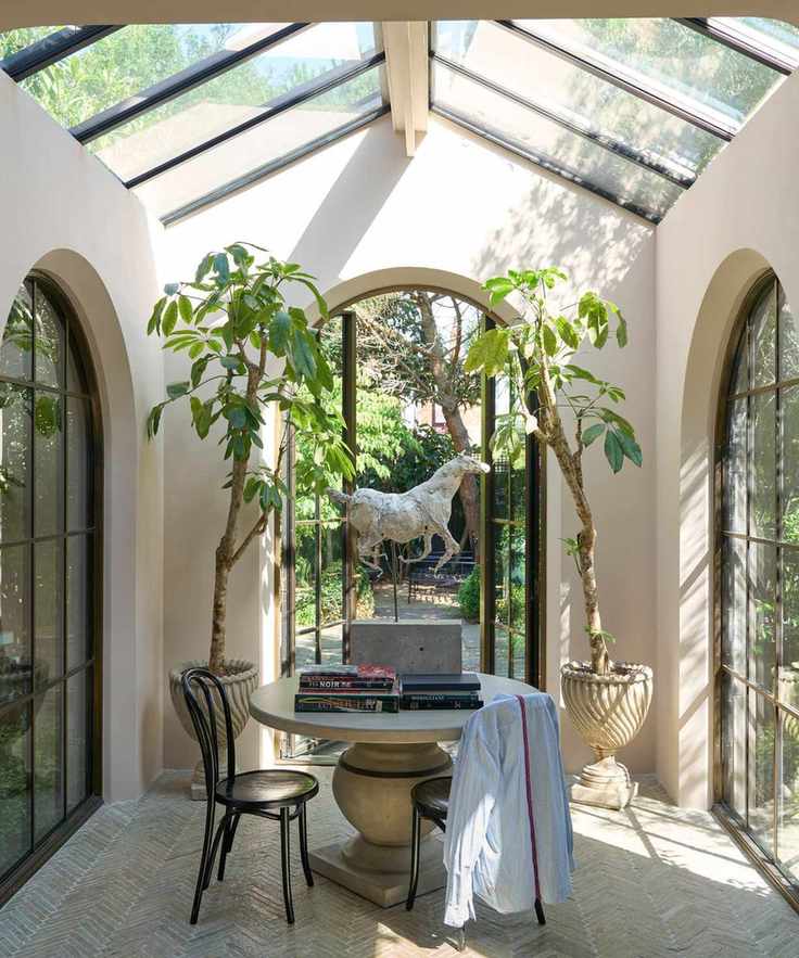 A garden room with bright natural light and pale pink walls.
