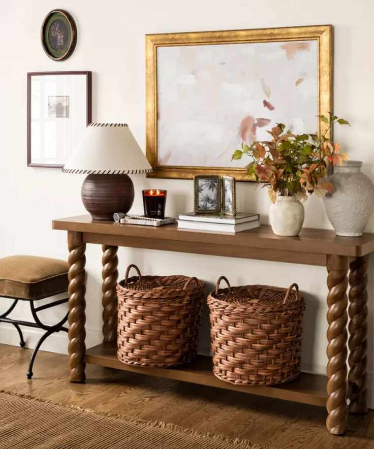 entryway table styled for the shea mcgee x target collaboration with a dark walnut twisted wooden console table styled with a lamp, baskets, and a vase