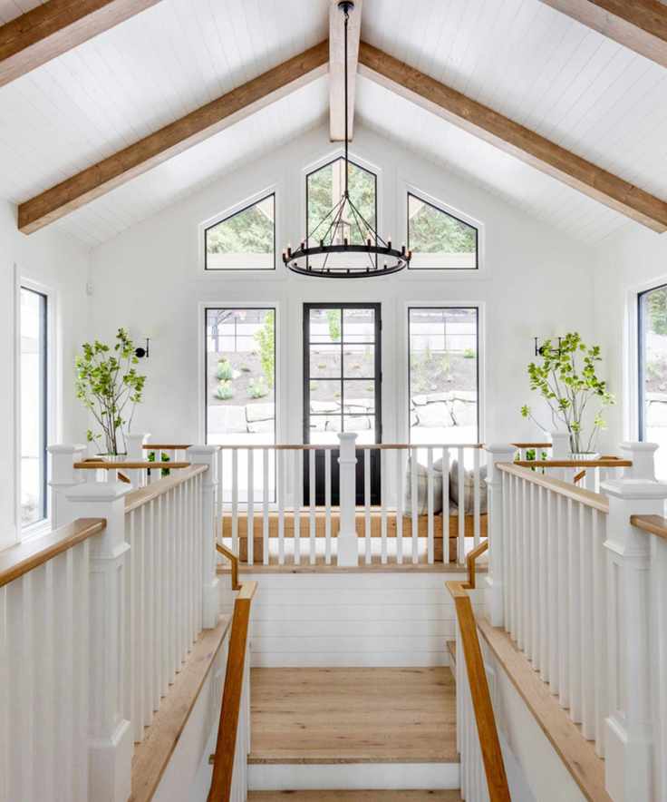 A white landing with a chandelier and a staircase